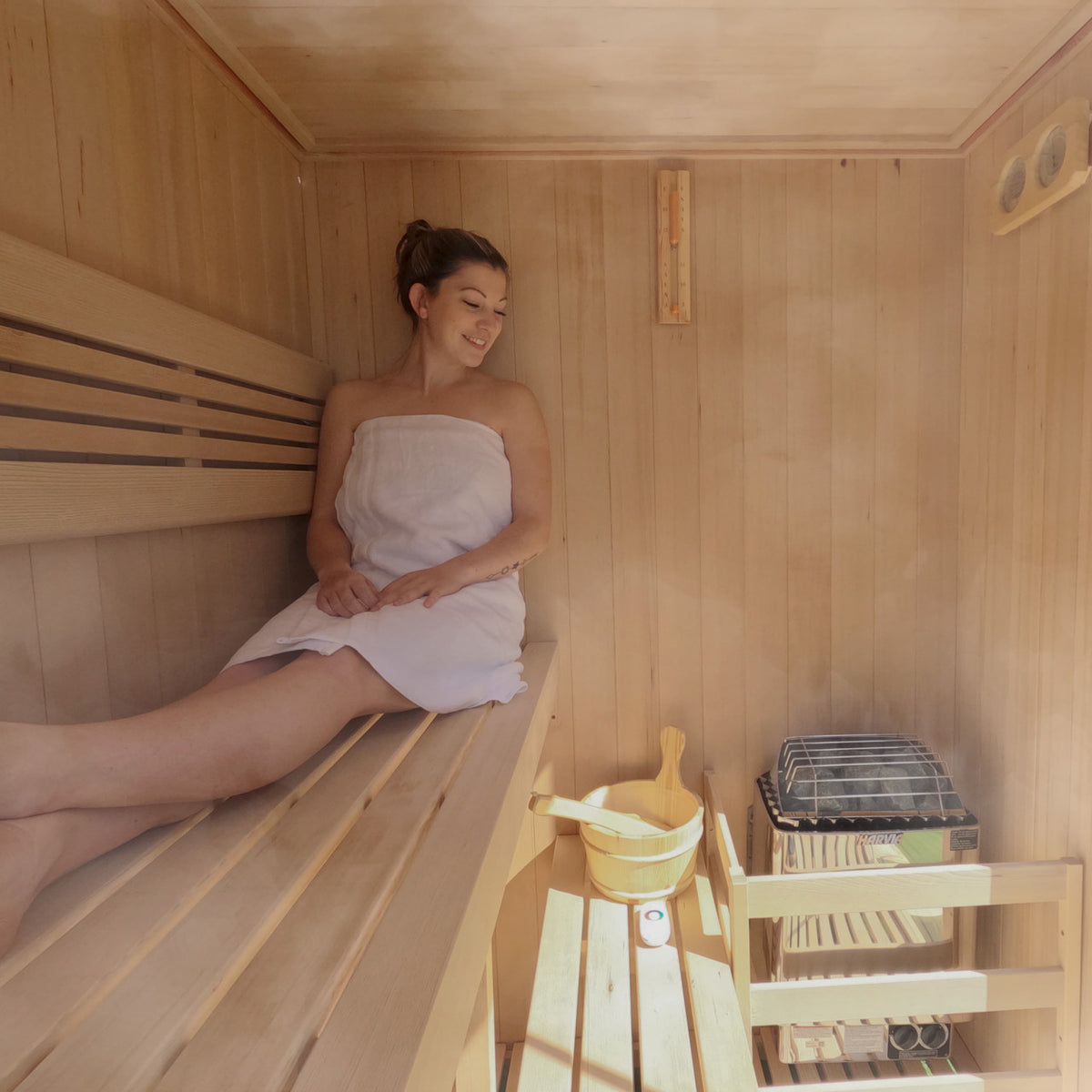 A woman using an Aleko Canadian Hemlock Indoor Wet/Dry Sauna with LED Lights 4/6 Person with 4.5 kW UL Certified Heater.