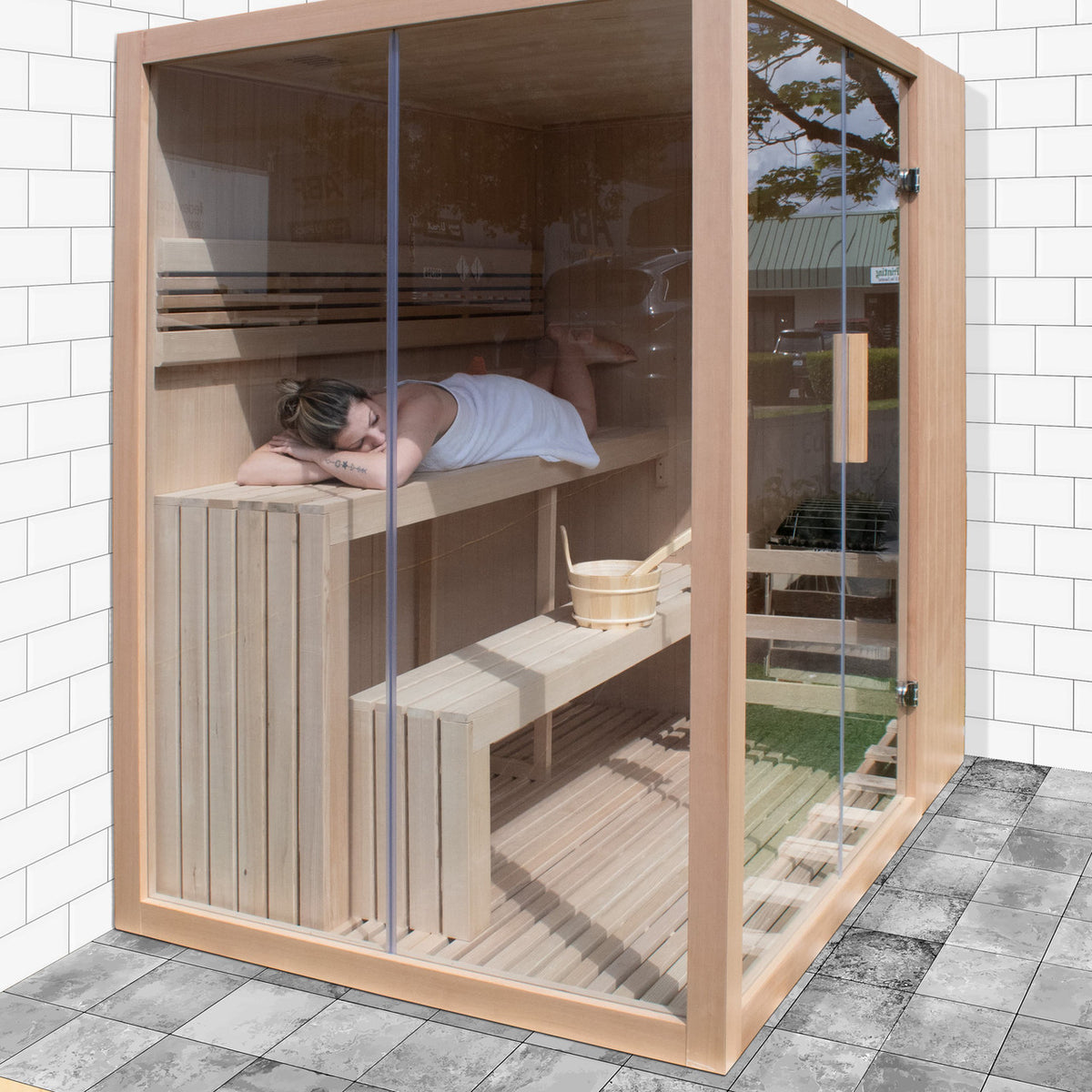 A woman using an Aleko Canadian Hemlock Indoor Wet/Dry Sauna with LED Lights 4/6 Person with 4.5 kW UL Certified Heater in an outdoor setting.