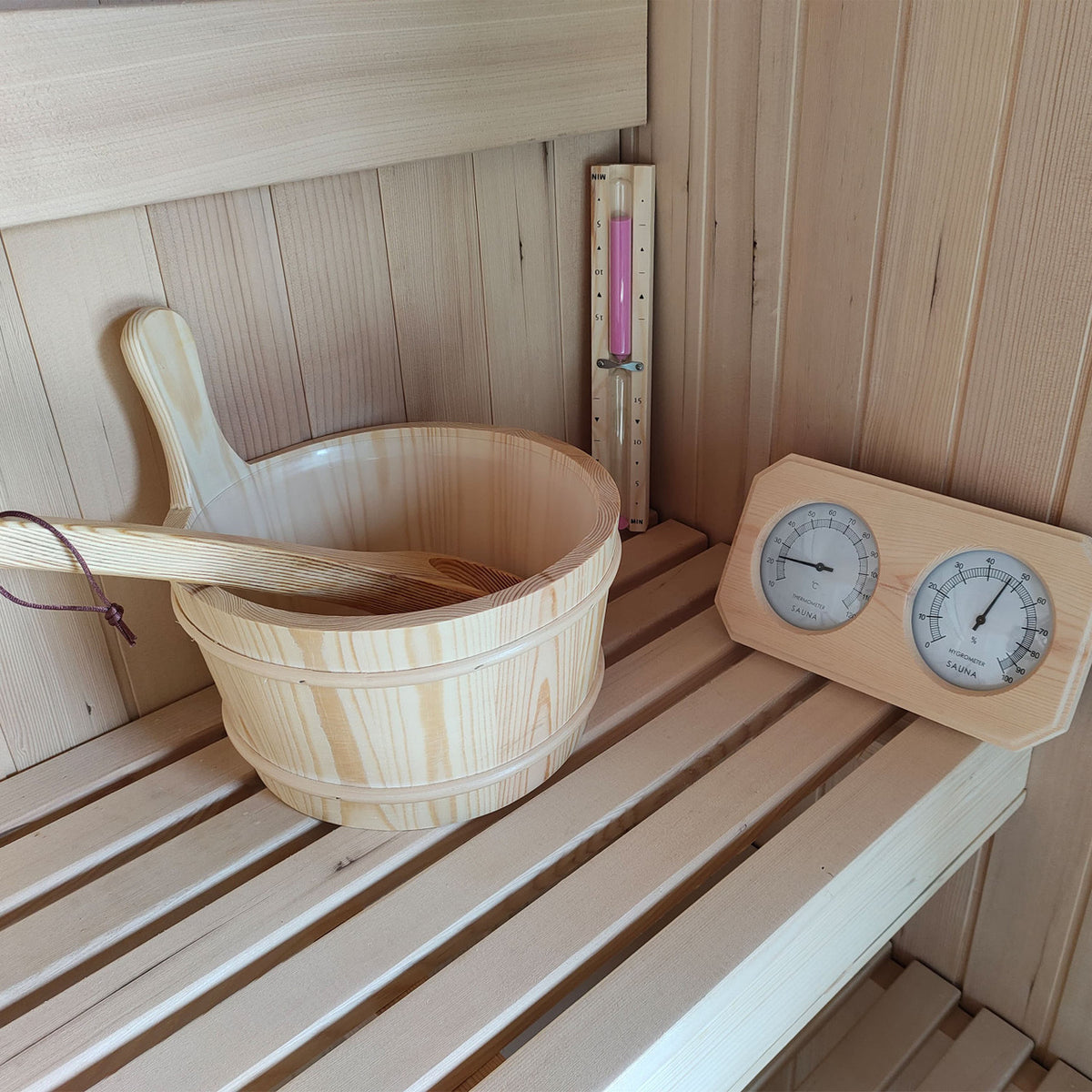 Accessories of Aleko Canadian Hemlock Wet/Dry Indoor Sauna 6 Person with 6kW UL Certified Heater, including a bucket, a traditional sand timer, and a thermometer.