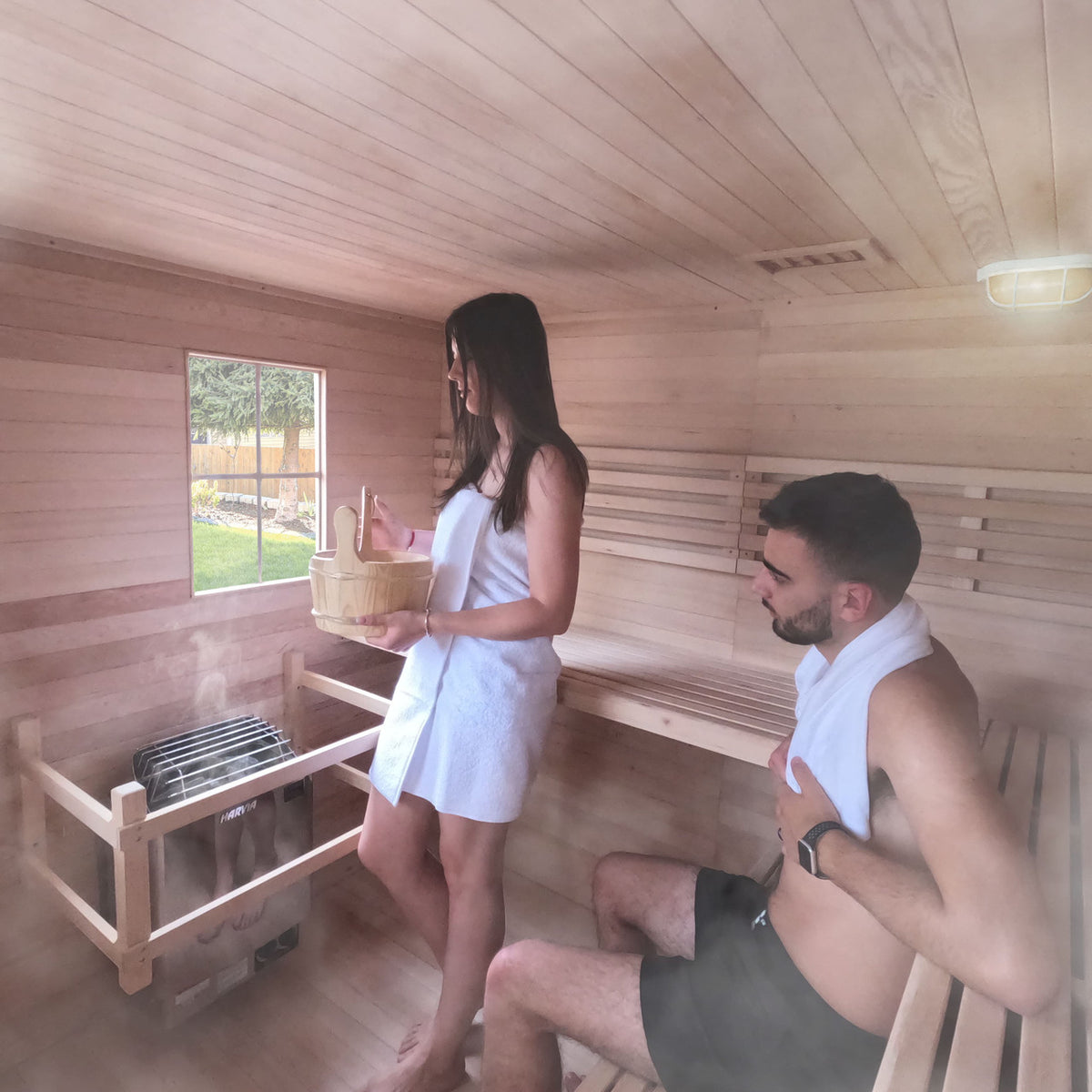 A couple using an Aleko Canadian Hemlock Wet/Dry Outdoor Sauna Asphalt Roof 5 Person with 6 kW Electric Sauna Heater.