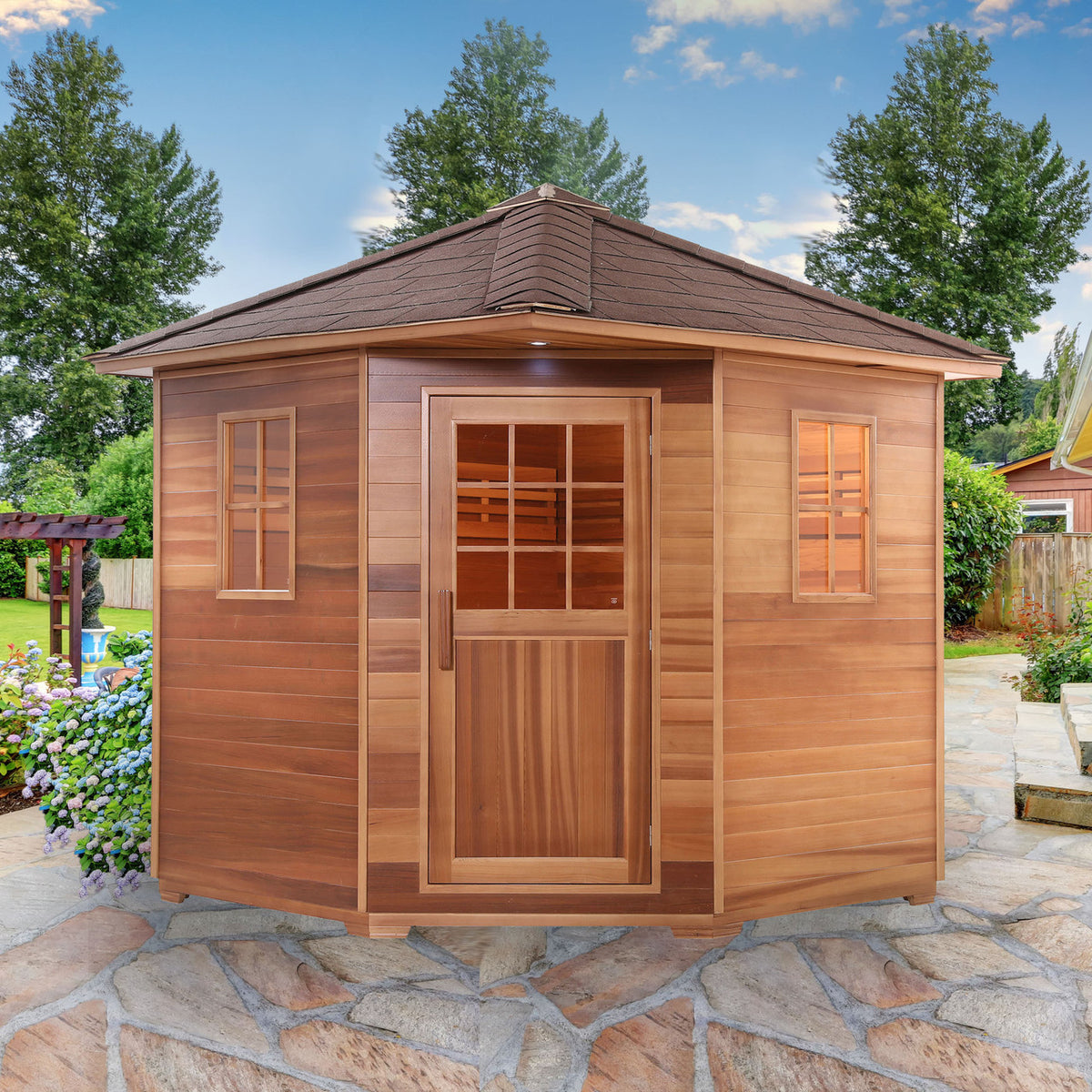 Aleko Canadian Red Cedar Wet/Dry Outdoor Sauna with Asphalt Roof 8 Person with 8 kW Electric Sauna Heater in a garden.