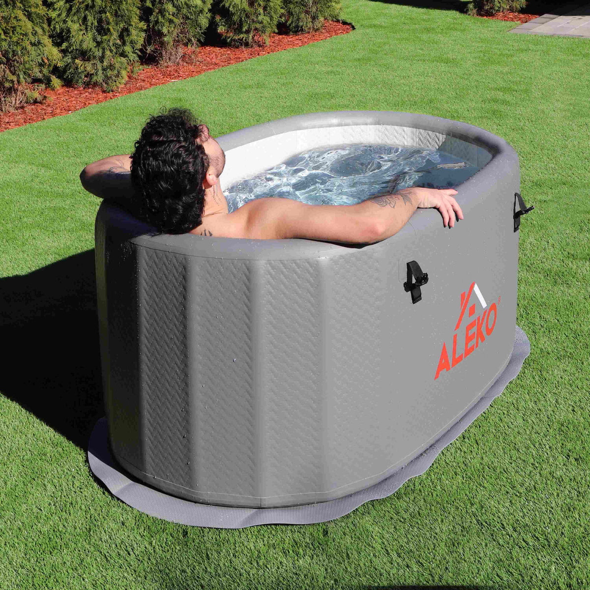 A man having a cold therapy session in an outdoor setting with an Aleko Inflatable Cold Plunge with Locking Lid and Carry Bag.