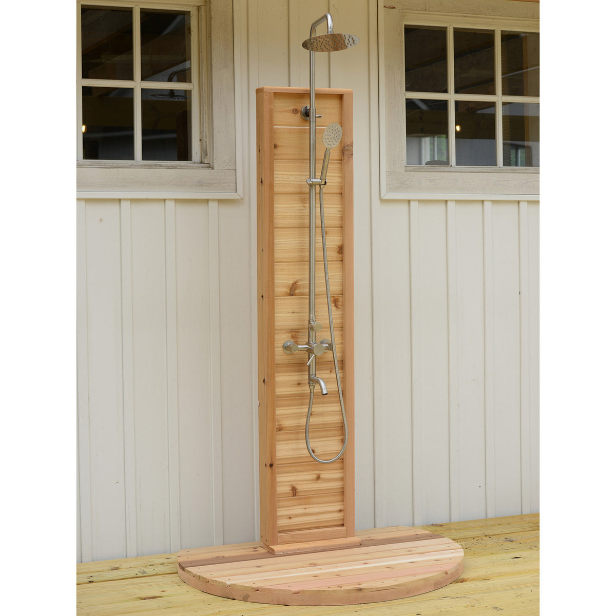 Aleko Tower Rinse Outdoor Shower installed on wooden deck next to white building.