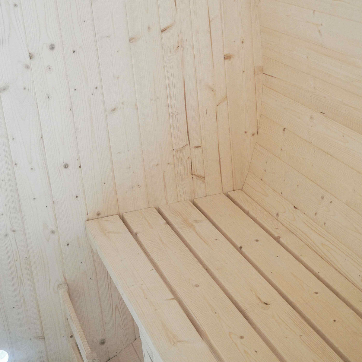 Bench detail of Aleko White Finland Pine Wet/Dry 6/8 Person Outdoor Barrel Sauna with Front Porch Canopy and 8 kW Harvia KIP Electric Sauna Heater.