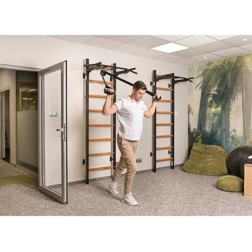 A man using a BenchK 221 Wall Bars and Gymnastic Ladders black version.