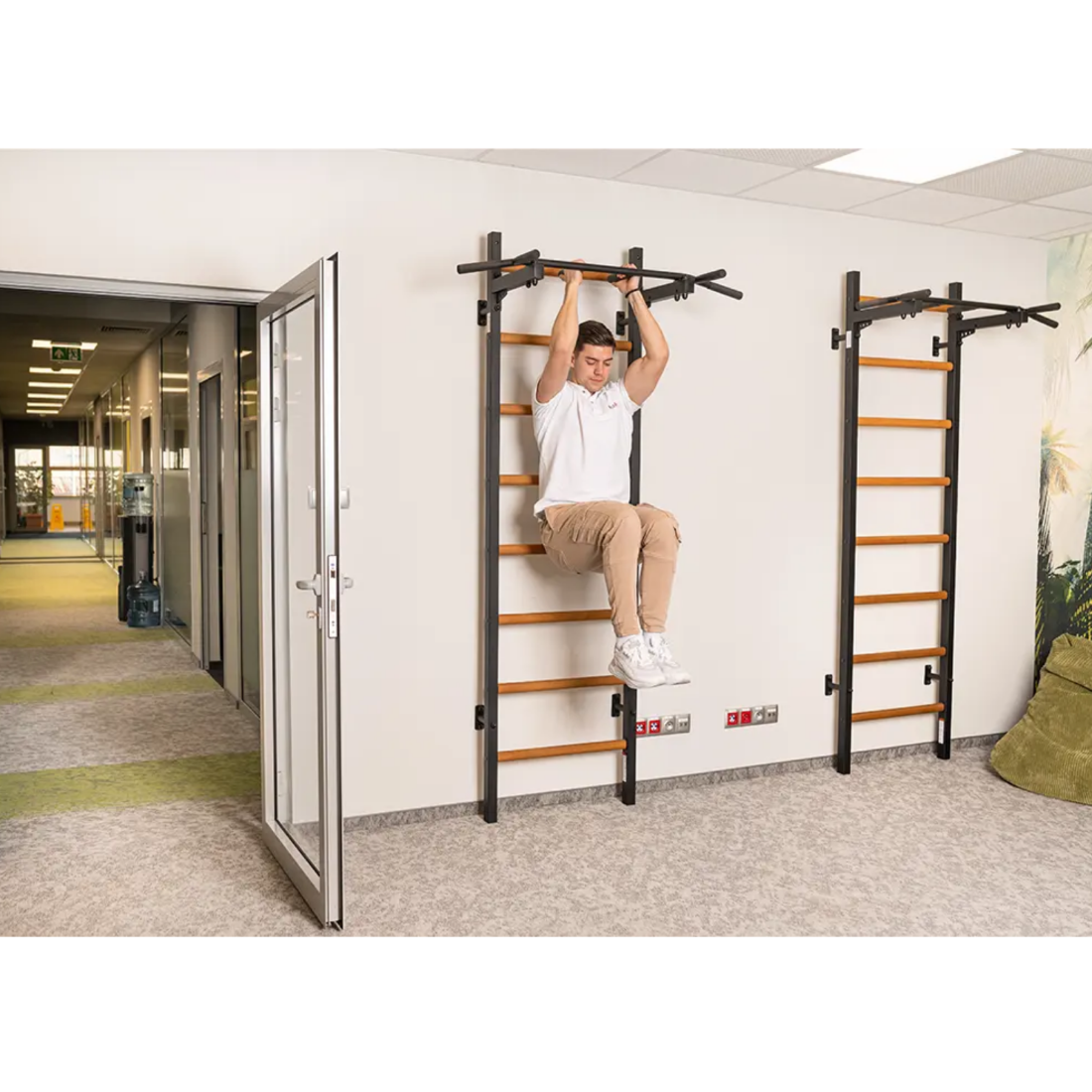 A man exercising his core using a BenchK 221 Wall Bars and Gymnastic Ladders black version.