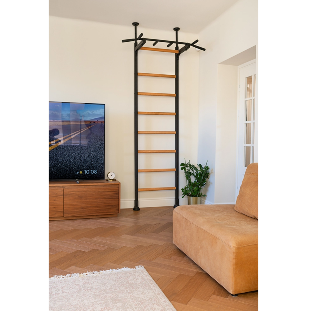 Front view of BenchK 521 Wall Bars and Gymnastic Ladders black version with pull-up bar installed in a living room.