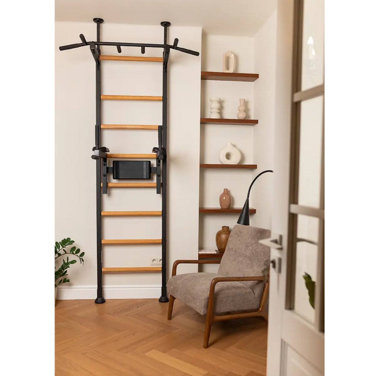 BenchK 522 Wall Bars and Gymnastic Ladders black version with pull-up bar and dip bar with back support and armrest installed in a living room.