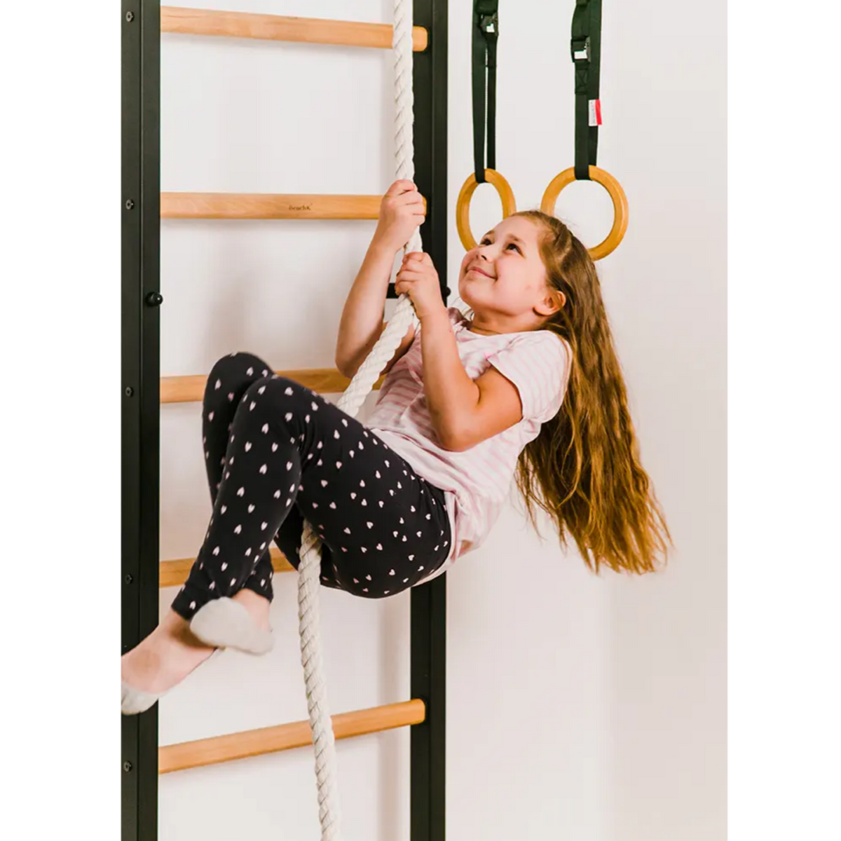 A kid playing with BenchK 721 Wall Bars + A076/A204 Gymnastic Accessories black version.