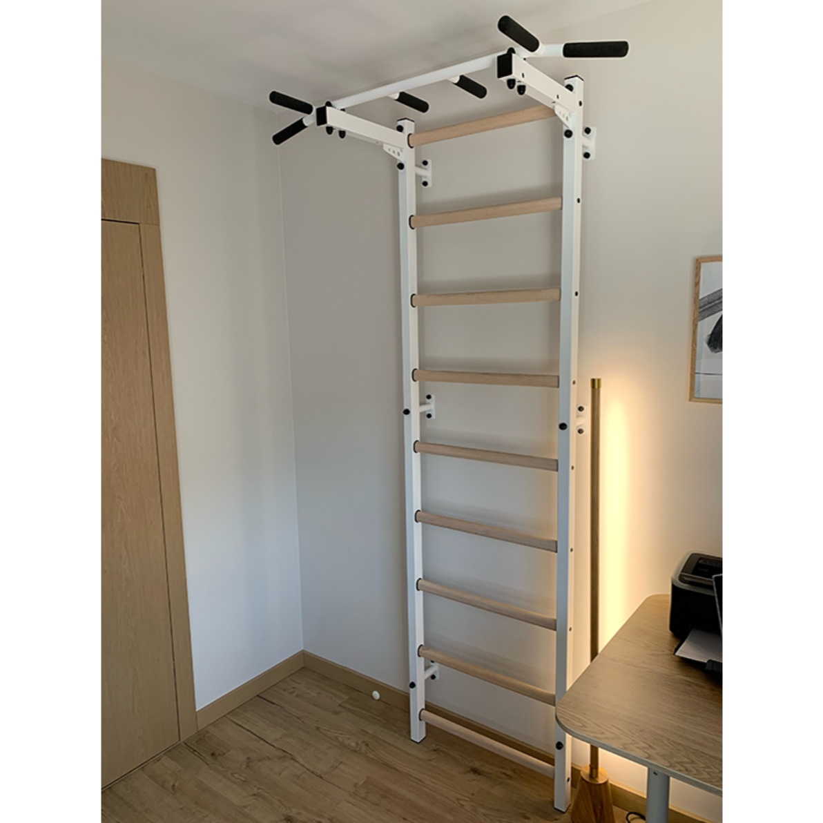 BenchK 721 Wall Bars and Gymnastic Ladders with pull-up bar white version installed in a bedroom.