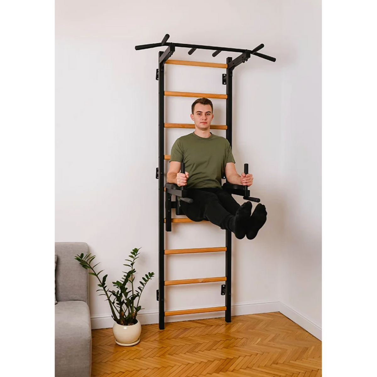 A man using BenchK 722 Wall Bars and Gymnastic Ladders black version installed in a living room.