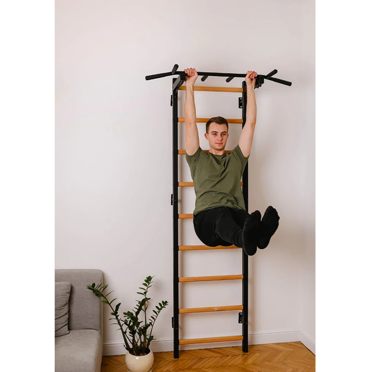 A man doing pull ups with BenchK 722 Wall Bars and Gymnastic Ladders black version installed in a living room.