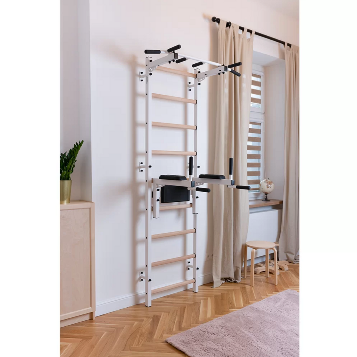 BenchK 722 Wall Bars and Gymnastic Ladders white version with pull-up bar and dip bar with back support and arm rest installed in a living room.