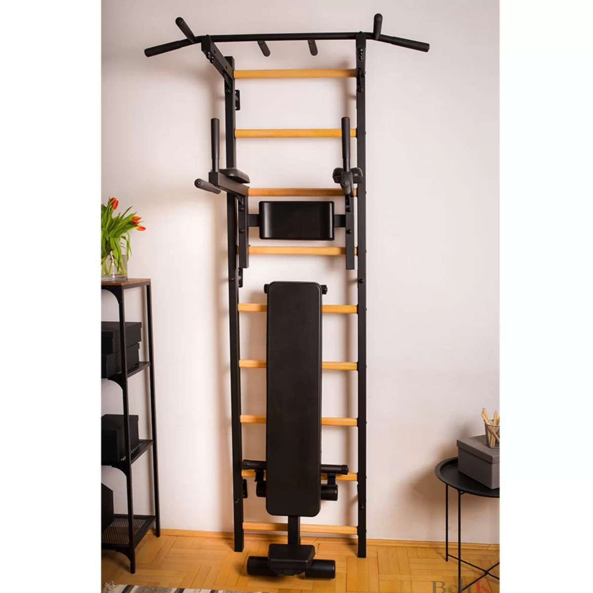 Front view of BenchK 723 Wall Bars and Gymnastic Ladders black version with pull-up bar, dip bar and workout bench installed in a living room.