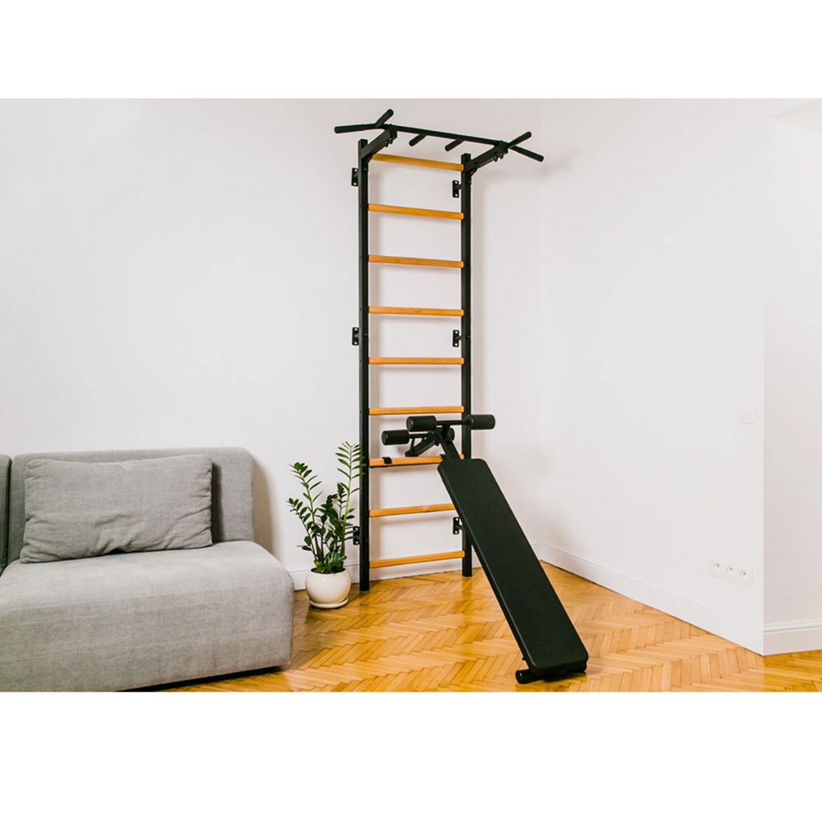 BenchK 723 Wall Bars and Gymnastic Ladders black version with pull-up bar and workout bench on installed in a living room.