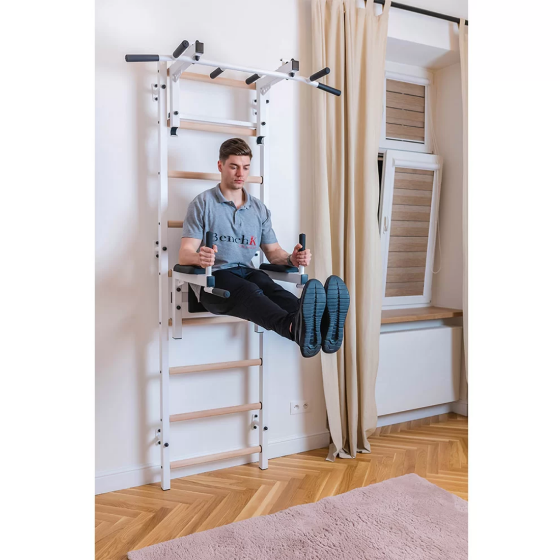 A man exercising with BenchK 732 Wall Bars and Gymnastic Ladders white version installed in a bedroom.