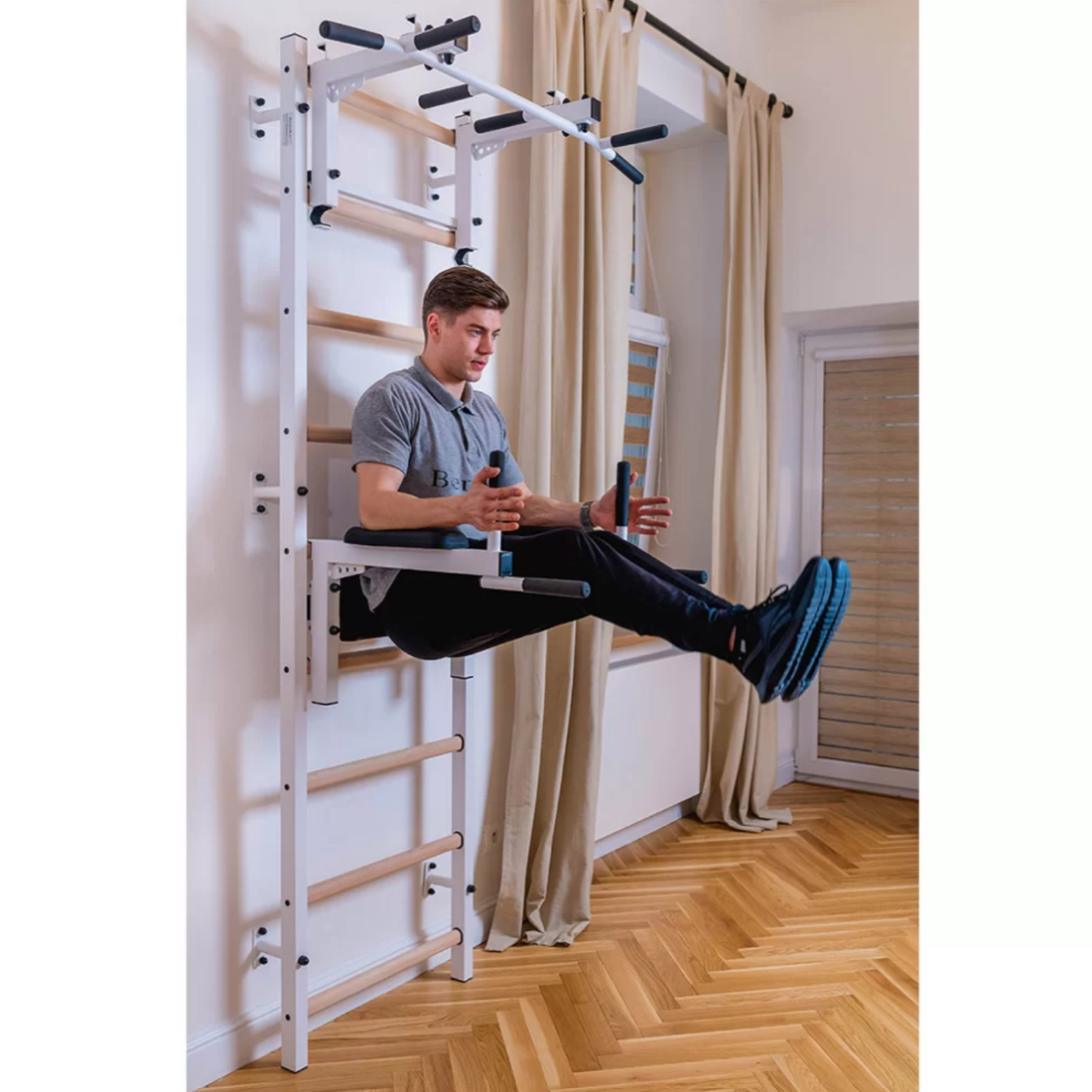 A man using the dip bar of BenchK 732 Wall Bars and Gymnastic Ladders white version installed in a bedroom.