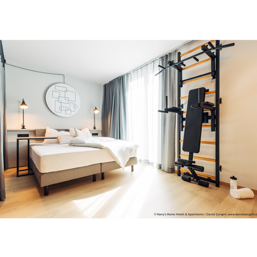 BenchK 733 Wall Bars and Gymnastic Ladders black version with pull-up bar, dip bar and workout bench installed in a bedroom.