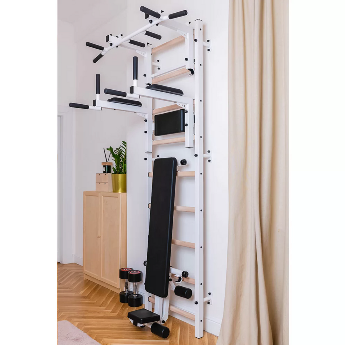 BenchK 733 Wall Bars and Gymnastic Ladders white version with pull-up bar, dip bar and workout bench installed in a bedroom.