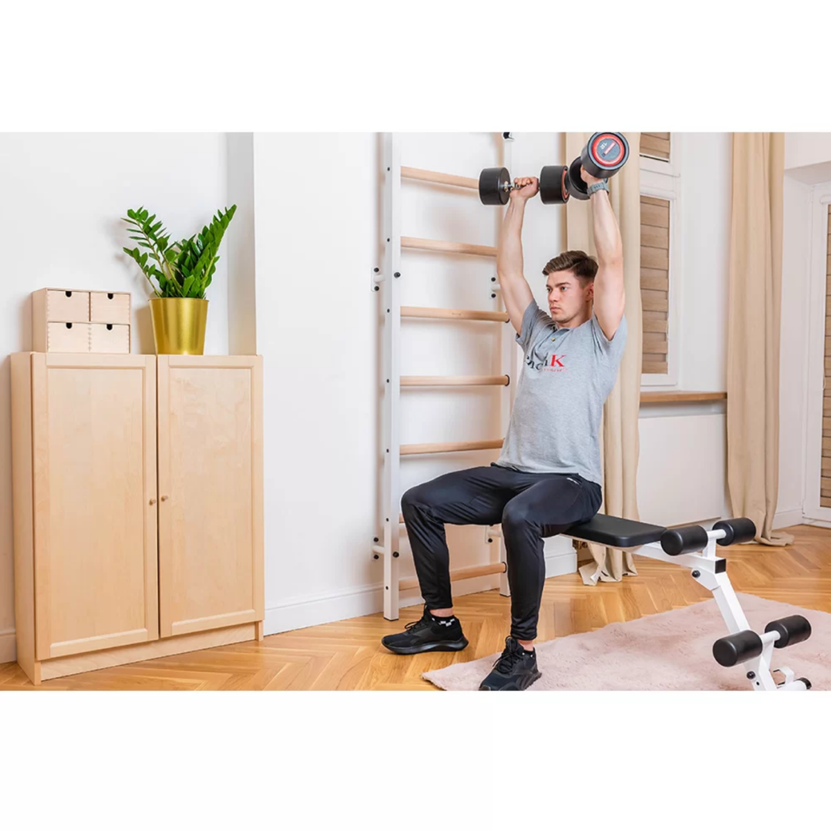 A man exercising with BenchK B1 Workout Bench white version installed in a living room.