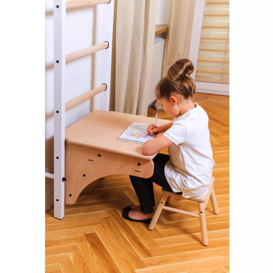 A child using BenchK BenchTop for Wall Bars light beech version as a desk.