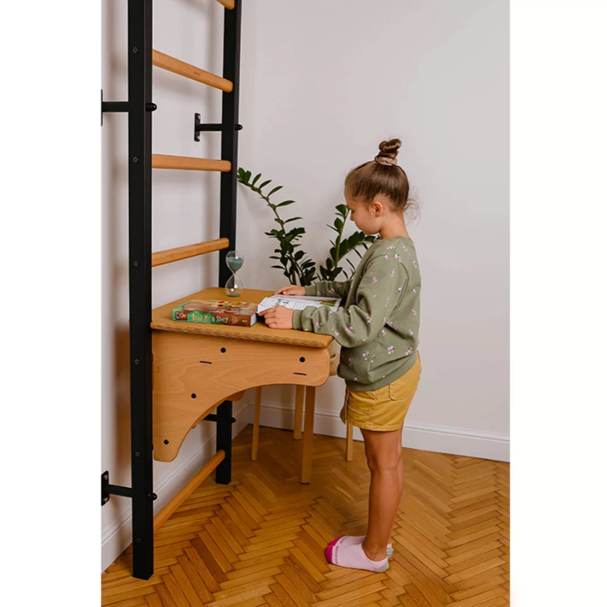 A child using BenchK BenchTop for Wall Bars oak version as a standing desk.