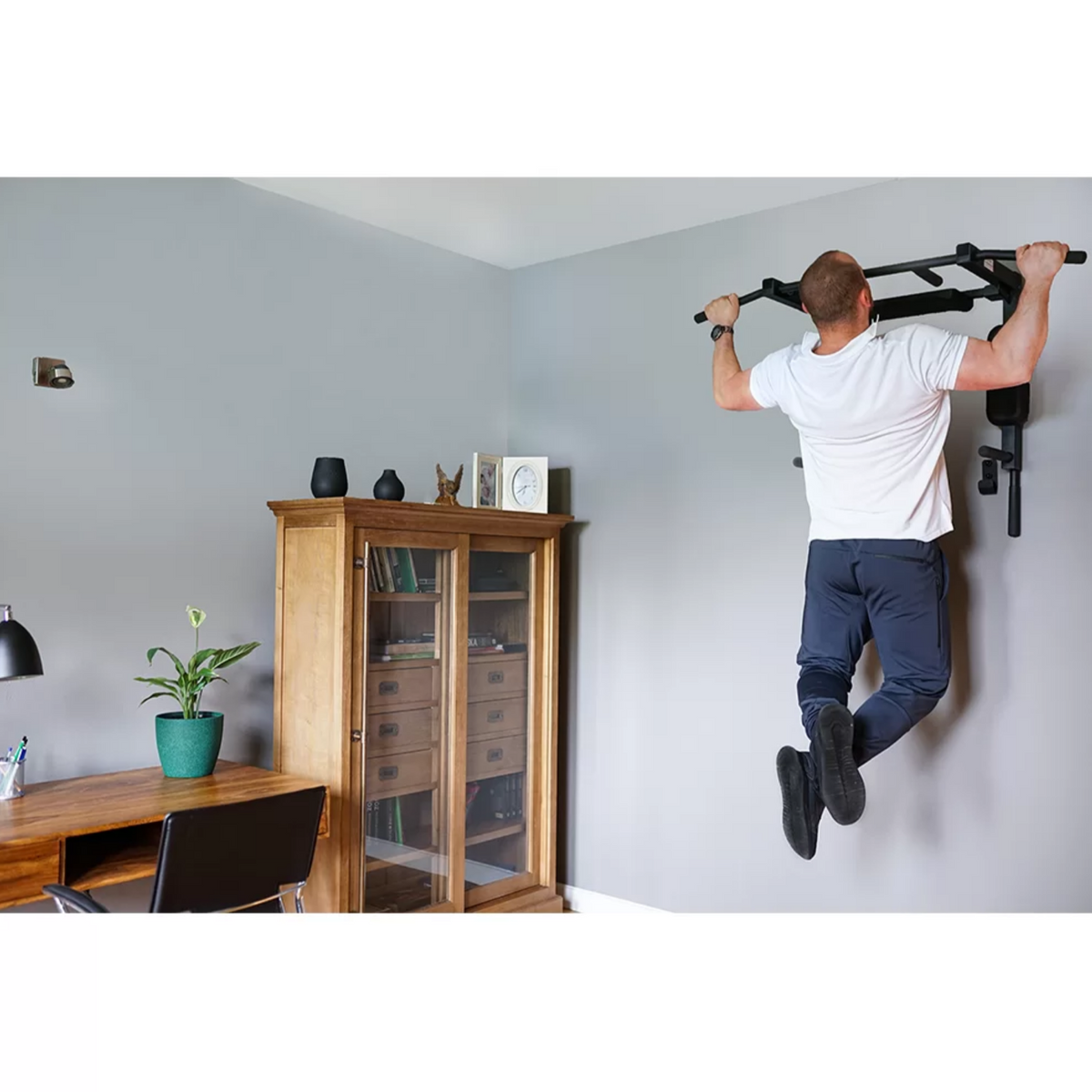 A man doing pull-ups with BenchK D8 Pull-Up Bar and Dip Bar 2 in 1 installed in his house.