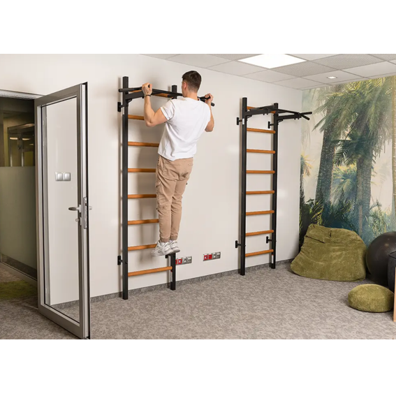 A man using a BenchK PB2 Steel Pull-Up Bar black version installed in a yoga studio.