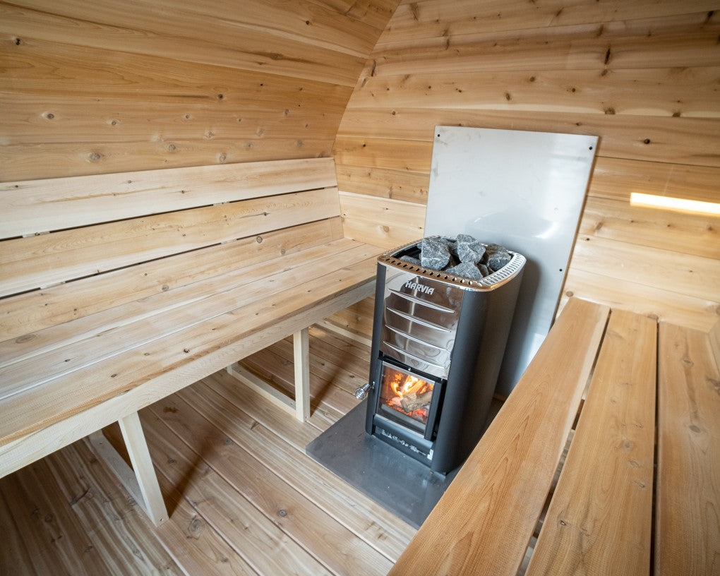 Inside view of MiniPOD Outdoor Sauna, showing its benches and sauna heater. 