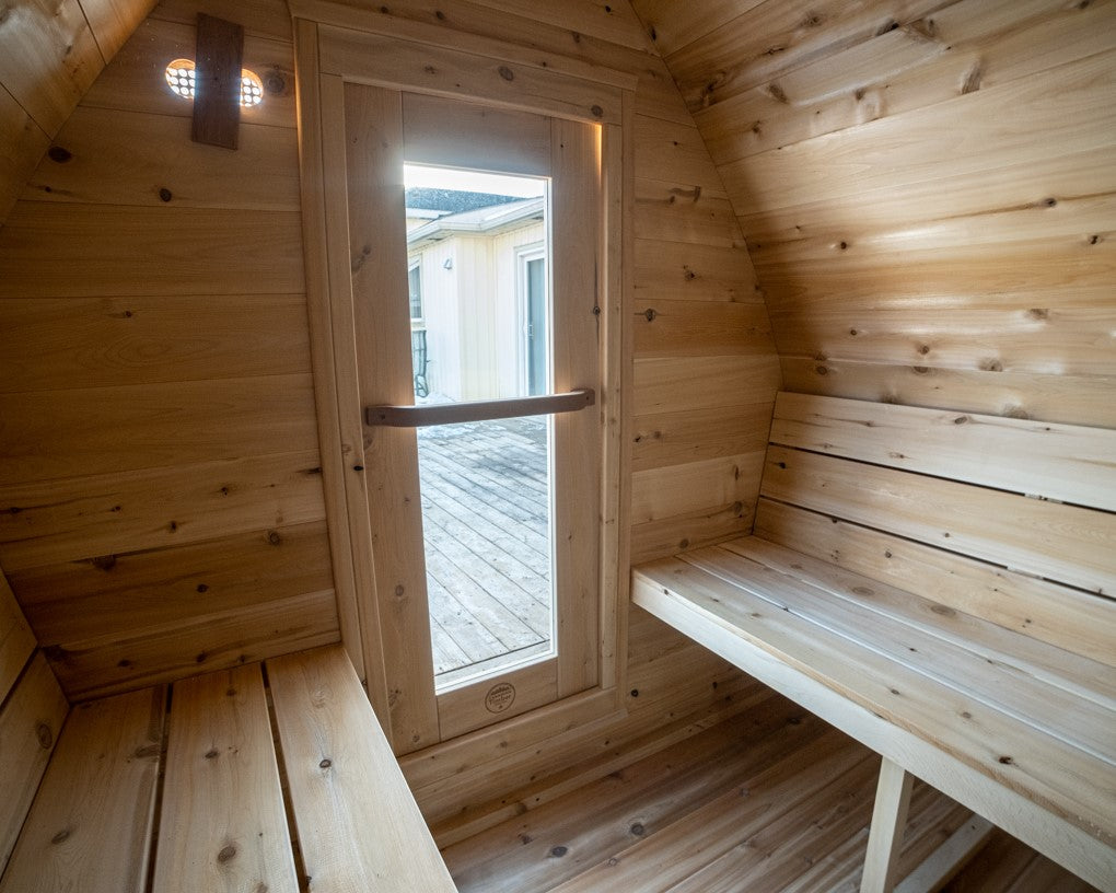 Interior view of MiniPOD Outdoor Sauna, showing its benches, and door with tempered glass. 