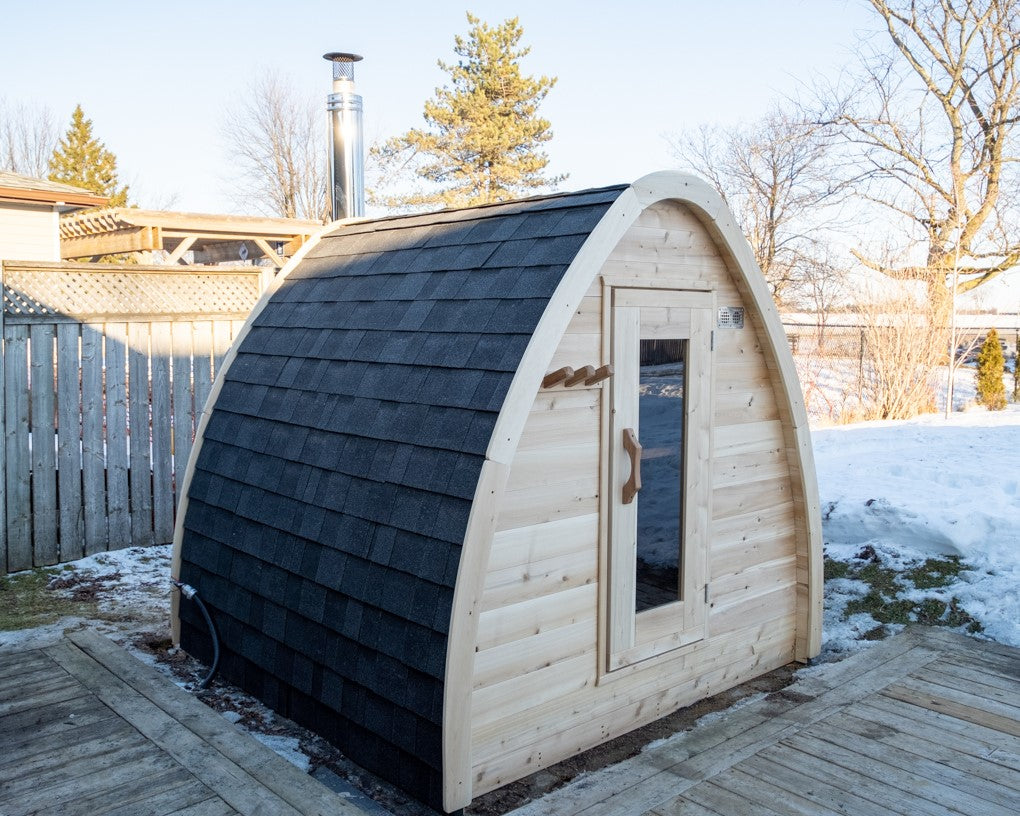 Diagonal view of MiniPOD Outdoor Sauna in a garden in winter surrounded by snow.