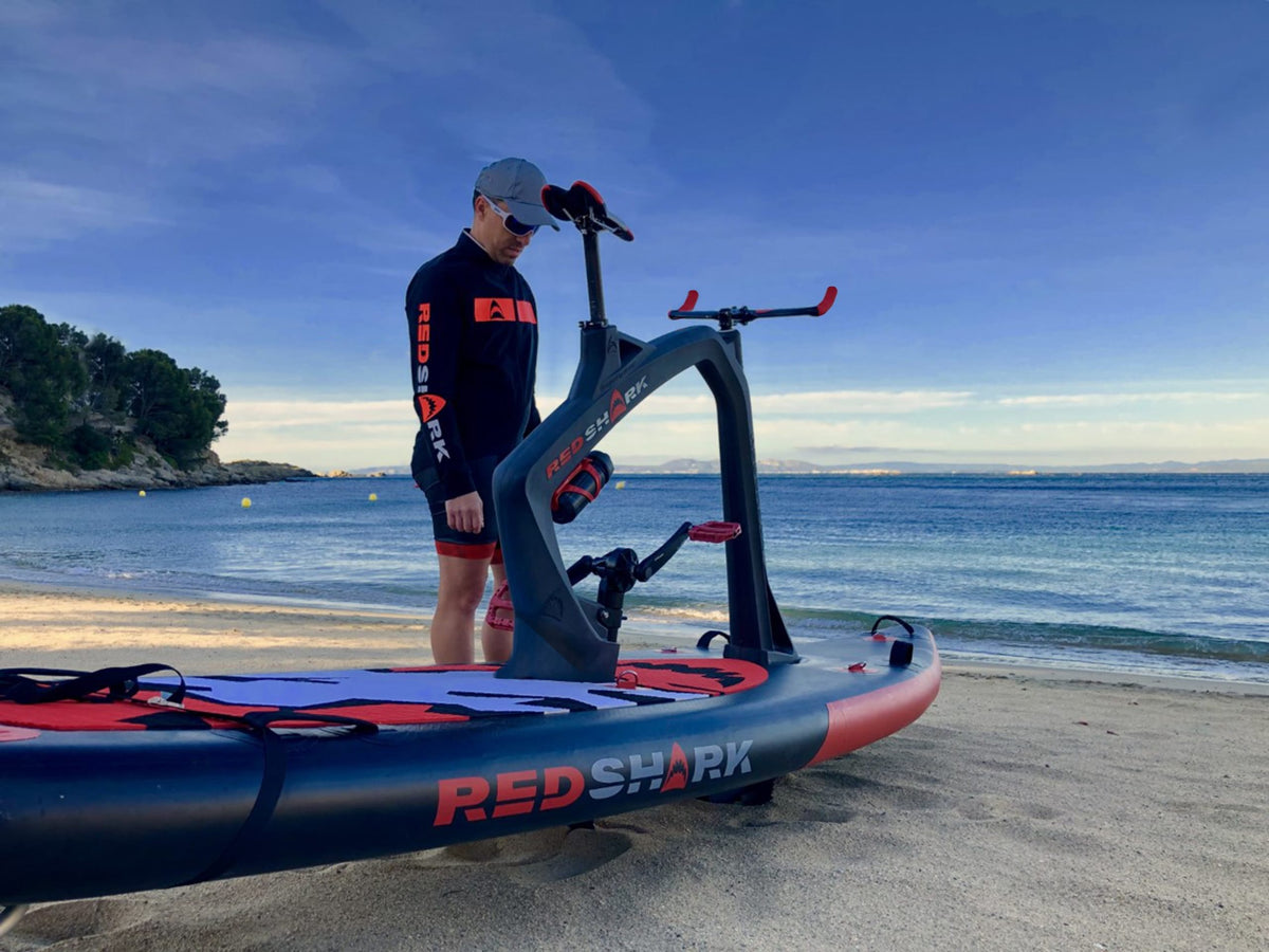 Fitness enthusiast on a Red Shark Fitness Bike Surf by the beach at sunrise.