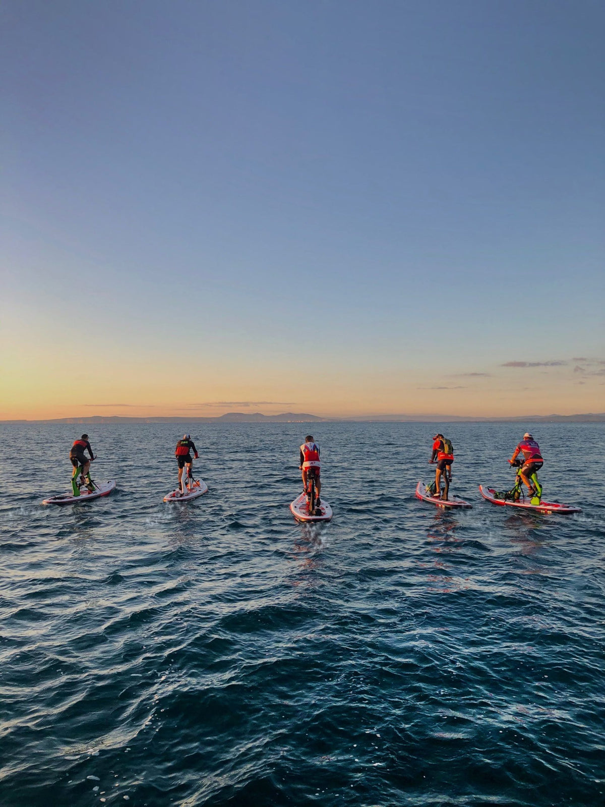 Group of Red Shark Fitness Bike Surfs during a sunset session on the open sea.