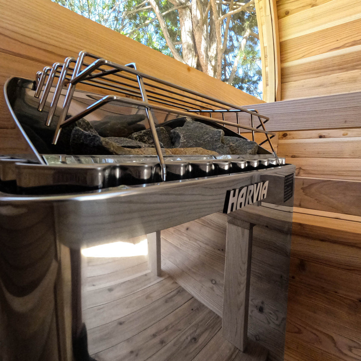 Close-up of Harvia KIP Electric Sauna Heater 8 kW installed in sauna with wooden bench and natural stones.