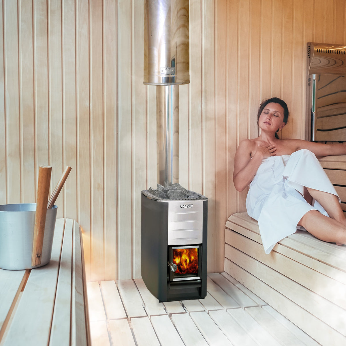 A woman using a Harvia M3 Wood Burning Sauna Heater and Chimney Kit in a sauna.