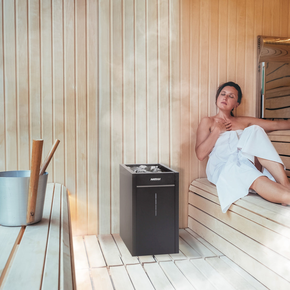 A woman in a sauna using a Harvia Virta Electric Sauna Heater with WiFi Remote Control Panel and 10.5 kW power.