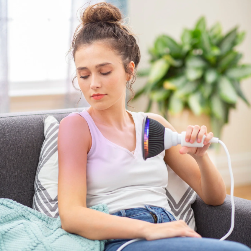 A woman using a Hooga Orange LED Light Therapy.