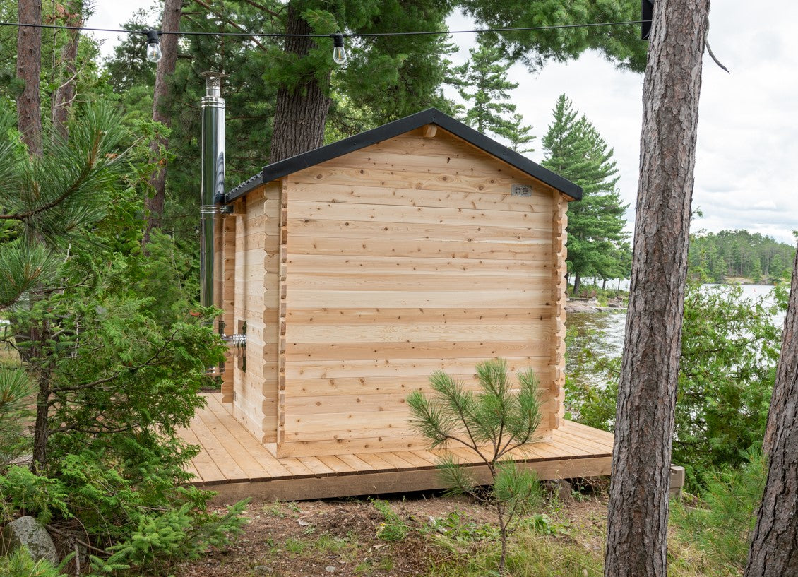 Back view of Georgian Cabin Outdoor Sauna in a natural setting, near a forest and a lake.