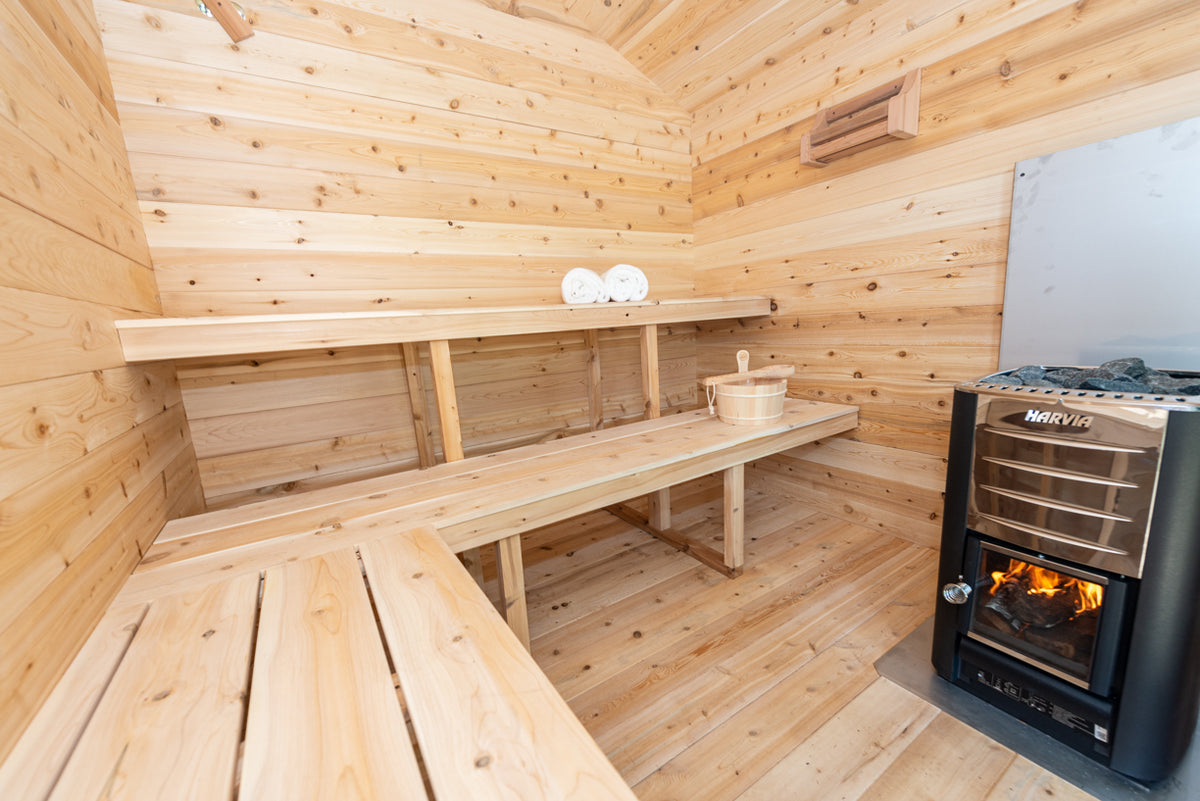 Interior view of  Leisurecraft Georgian Cabin Outdoor Sauna with the wood burning heater on and ready to use.