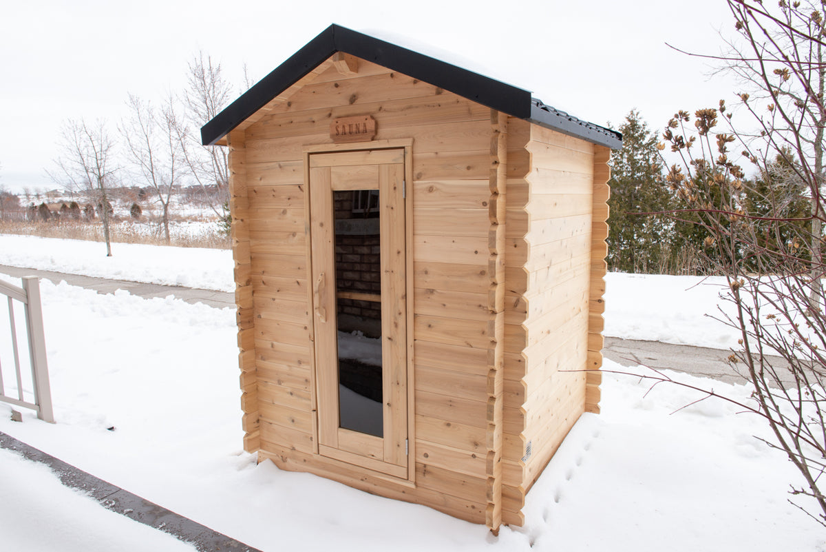 Diagonal view of Leisurecraft Canadian Timber Granby Cabin Outdoor Sauna in a winter outdoor setting with snow.