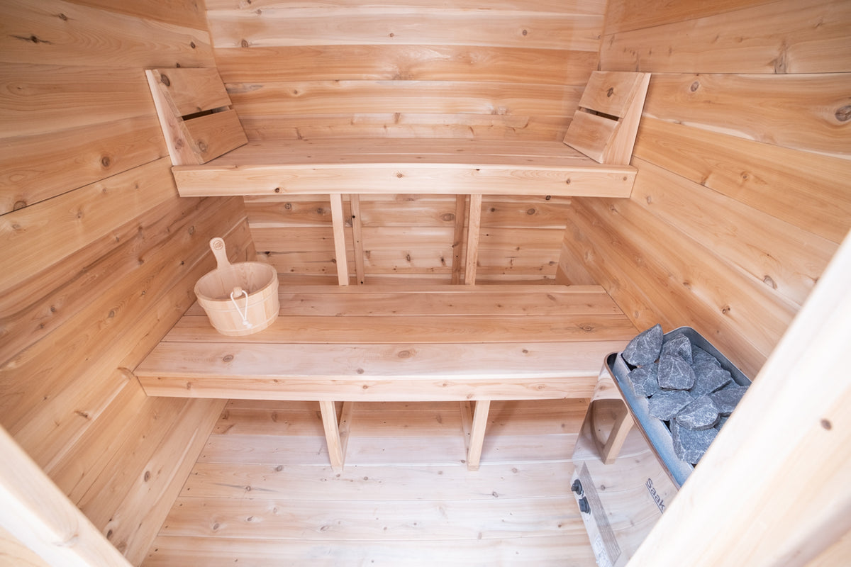 Interior view of a Leisurecraft Canadian Timber Granby Cabin Outdoor Sauna, showing the heater and two tier benches.