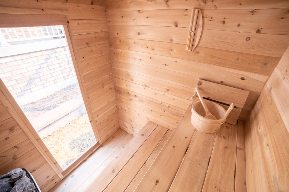 Interior view of a Leisurecraft Canadian Timber Granby Cabin Outdoor Sauna, showing the two tier benches, and door with tempered glass. 