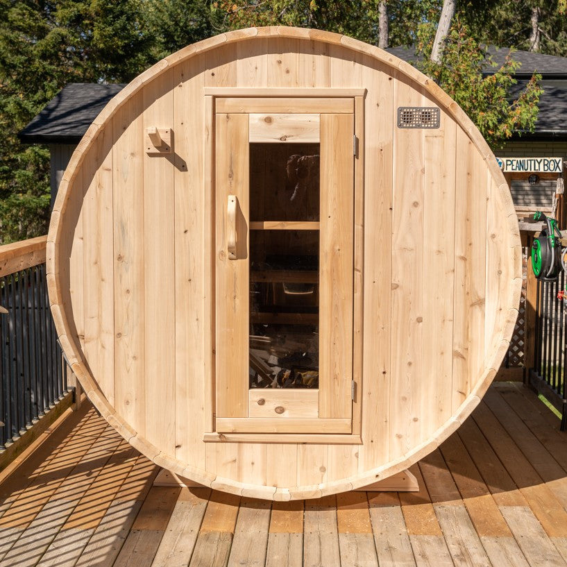 Front view of Leisurecraft Canadian Timber Harmony Barrel Sauna in an outdoor setting on a sunny day.