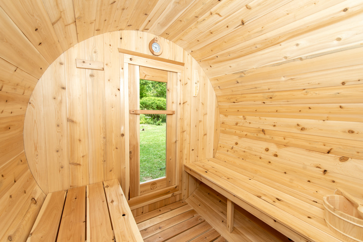 Interior view of Leisurecraft Canadian Timber Harmony Barrel Sauna showing its benches and tempered glass door.