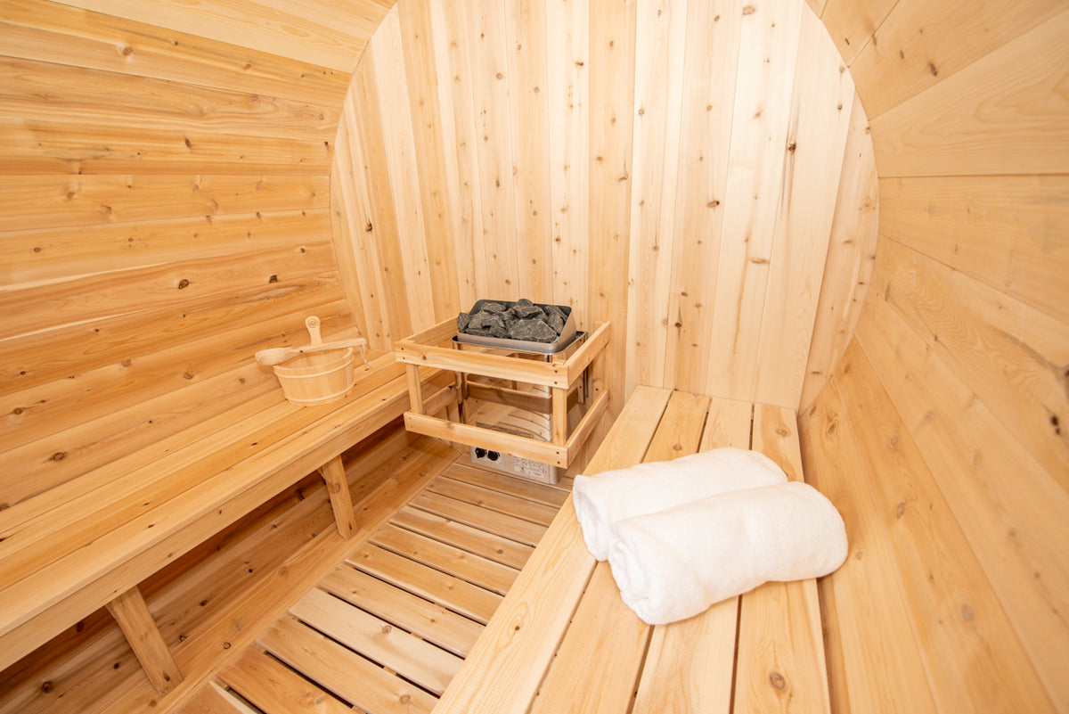 Close-up view of benches and heater of Leisurecraft Canadian Timber Harmony Barrel Sauna.