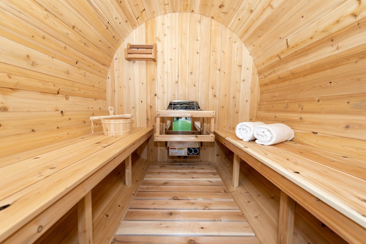 Interior view of Leisurecraft Canadian Timber Harmony Barrel Sauna showing its benches, floor and heater.