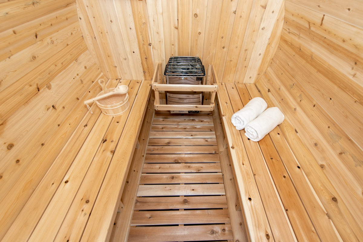 Interior view of Leisurecraft Canadian Timber Harmony Barrel Sauna with a focus on its flat floor, benches and heater.