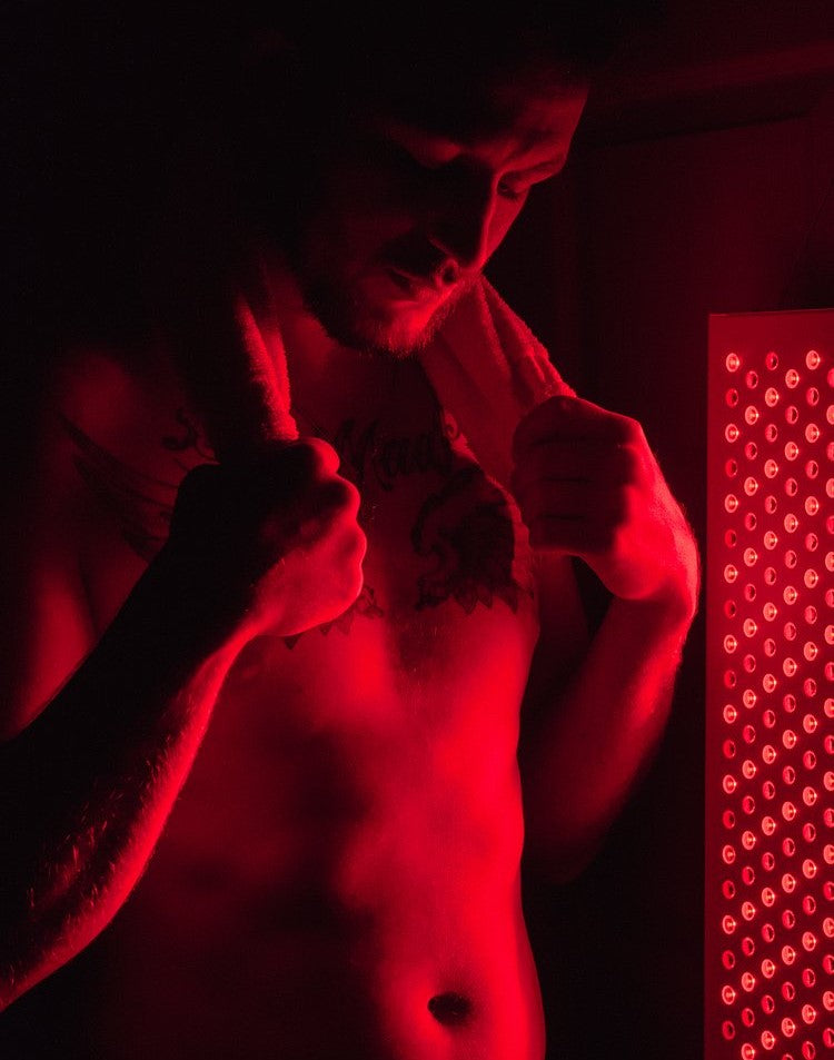 A man having a red light therapy session with an ORB Red/NIR Light MAX Panel after a workout.