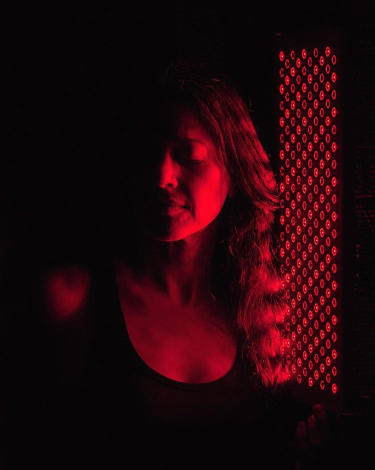 Close-up of a woman&#39;s face illuminated by the ORB Red/NIR Light Panel, demonstrating the panel&#39;s use in facial red light therapy.