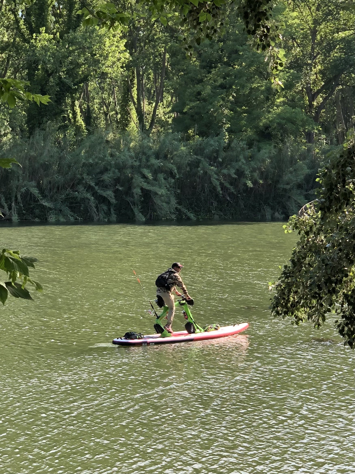 Fisherman on a Red Shark Adventure Bike Surf moving along the peaceful riverbank.